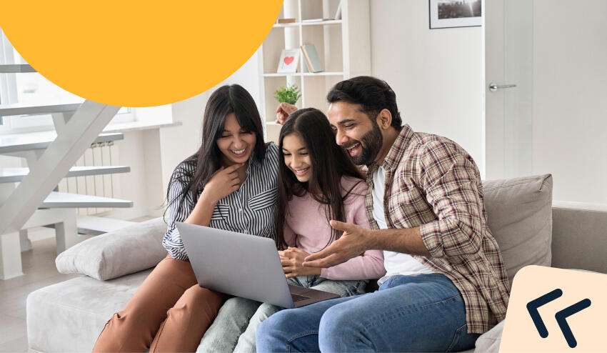 ​Papá, mamá e hija sentados en una silla revisan emocionados en su computador opciones universitarias